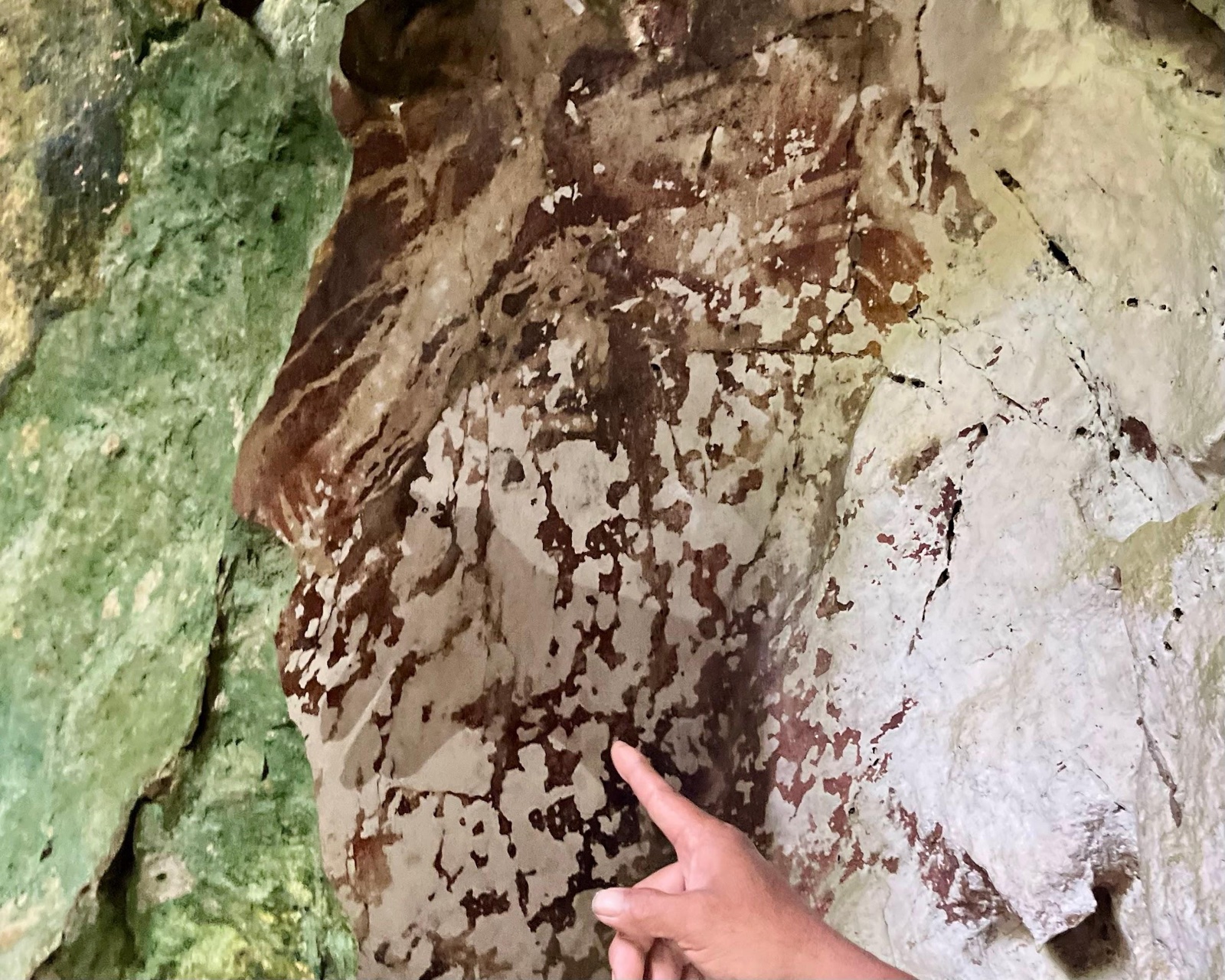 Hand painting surrounding rock surface, Leang Pettae, Maros, South Sulawesi. Photograph by Christine Toelle.